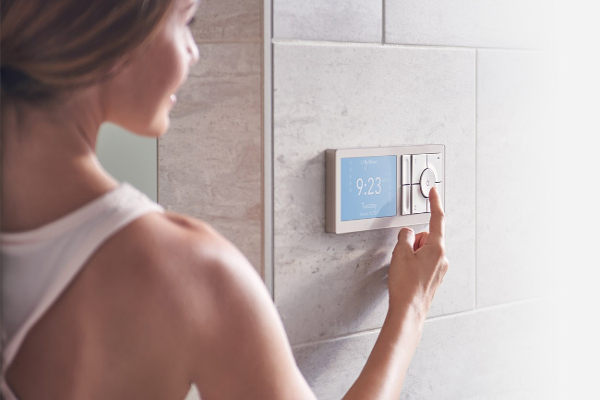 A woman uses a touchpad on a smart shower.